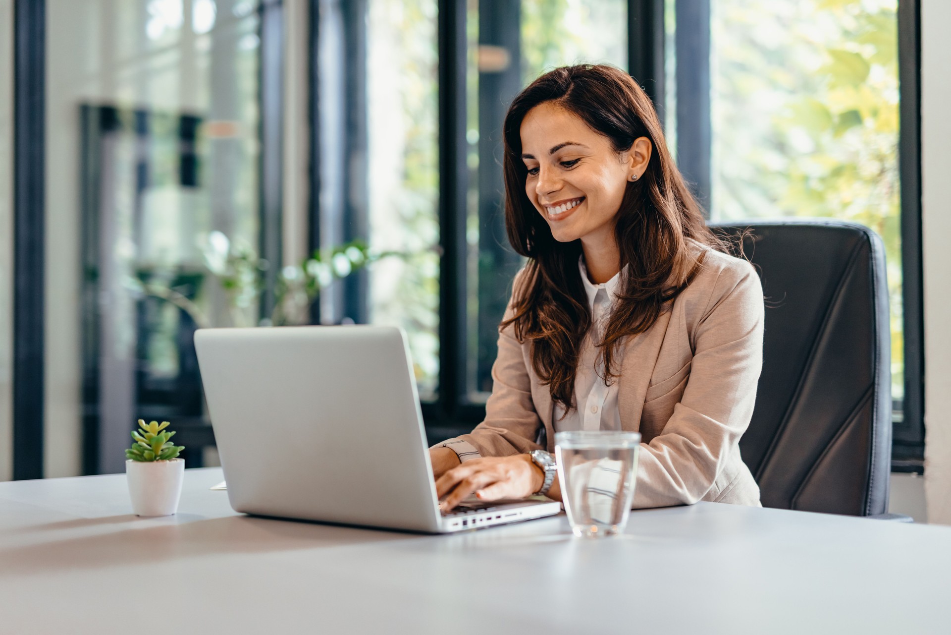 Professional woman at desk using laptop and sitting in modern office.